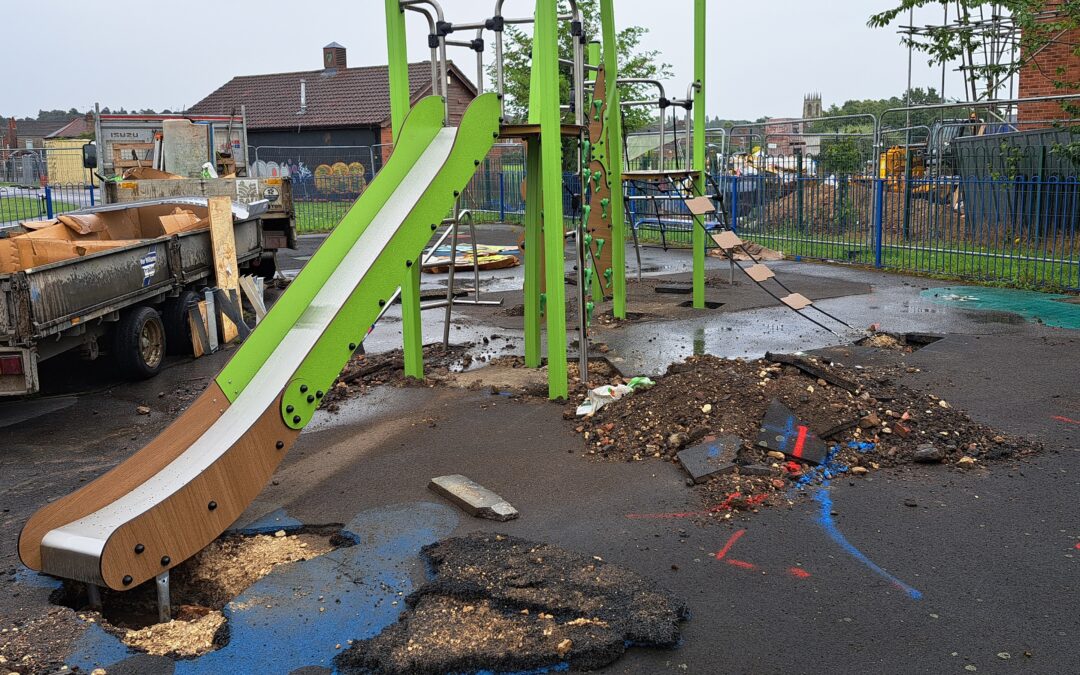 Green slide and play equipment, surrounded by the rubble from ongoing work.
