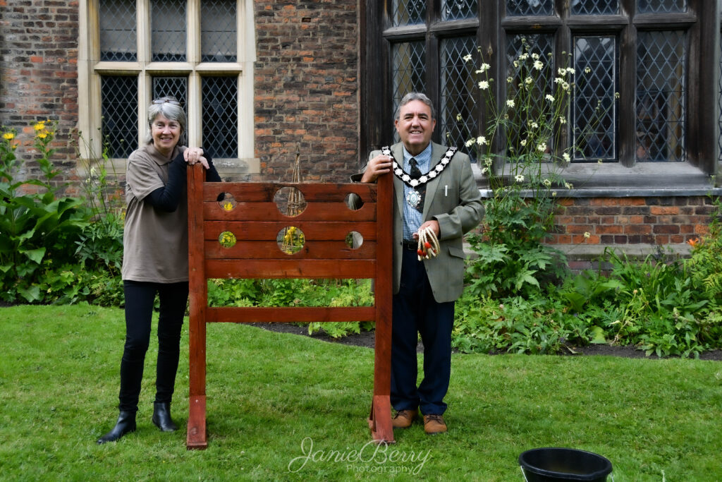 Cllr Woolley stood at the stocks with a member of the Gainsborough Old Hall team in front of the Old Hall.